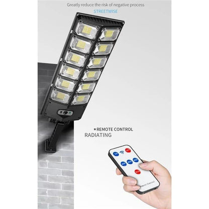 Solar sensor outdoor light mounted on a wall, with a remote control shown below.