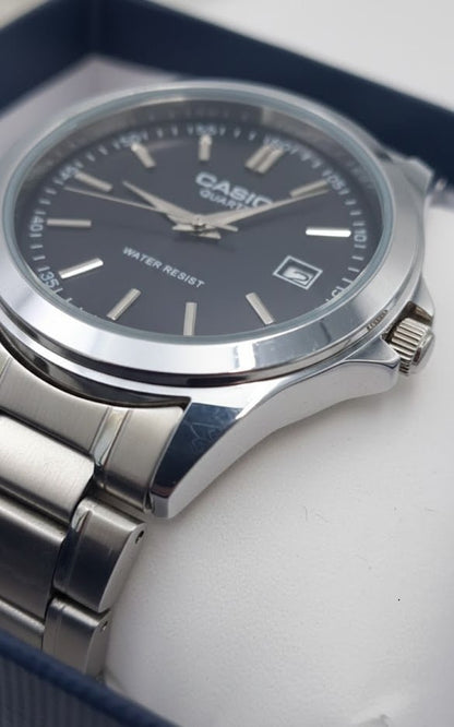 Casio watch close-up showing dark dial, date window, polished case, and metal bracelet