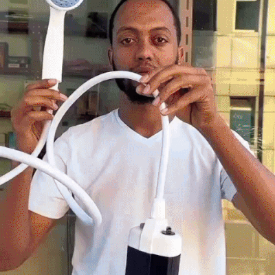 Handheld outdoor shower with white sprayer, flexible hose, and black-and-white pump unit