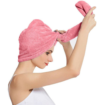 Pink hair drying cap towel wrapped around hair, with the long end being twisted.
