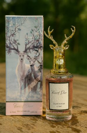 Forest Deer perfume in a clear bottle with gold antler cap beside its illustrated box.